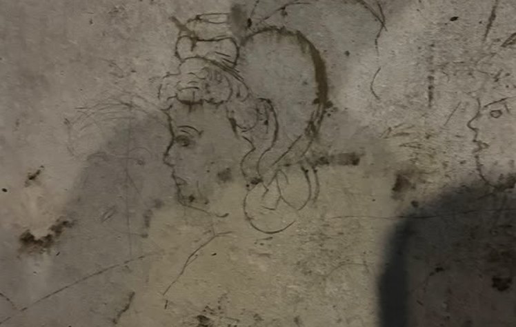 A wartime charcoal drawing on a tuff wall
